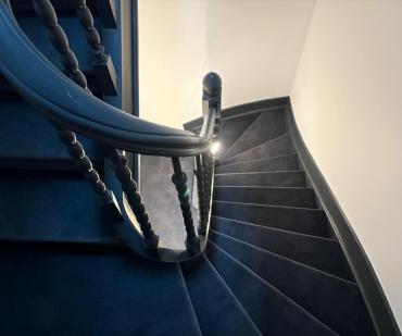 Finition du tapis anthracite autour de la rampe d'escalier